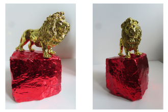Roter Löwe 2026, Plastikspielzeugfigur auf Pflasterstein, Imitation farbiges Blattgold